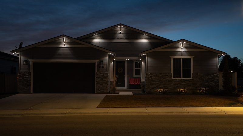 A large brick home lit in warm white at dusk